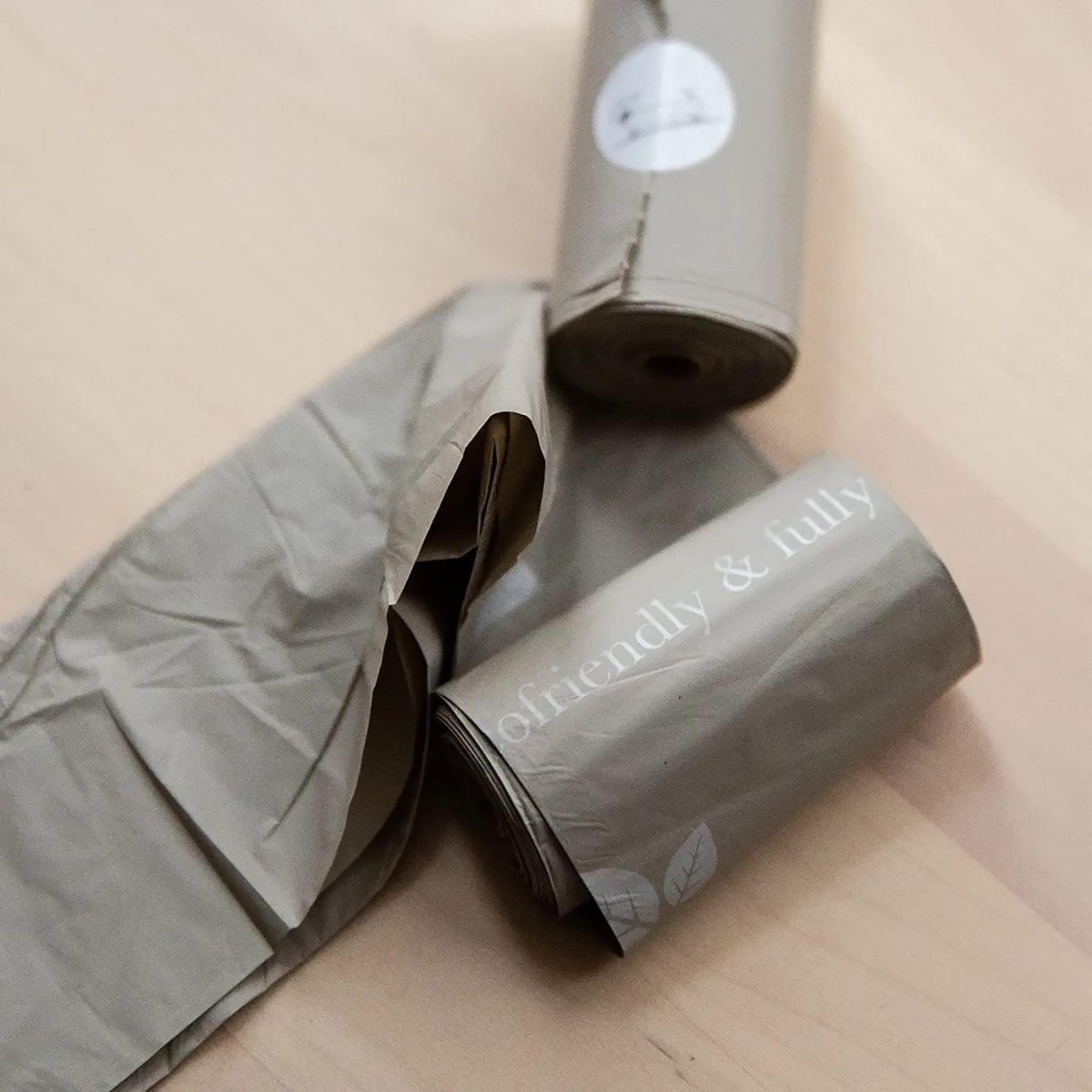 Two rolls of gray paper with 'friendly & fully' branding on a beige surface.