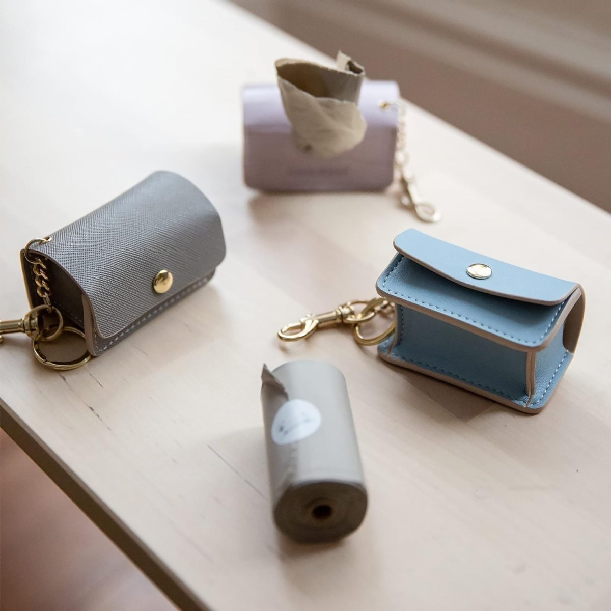 Two small leather pouches, one gray and one blue, on a light wooden surface.